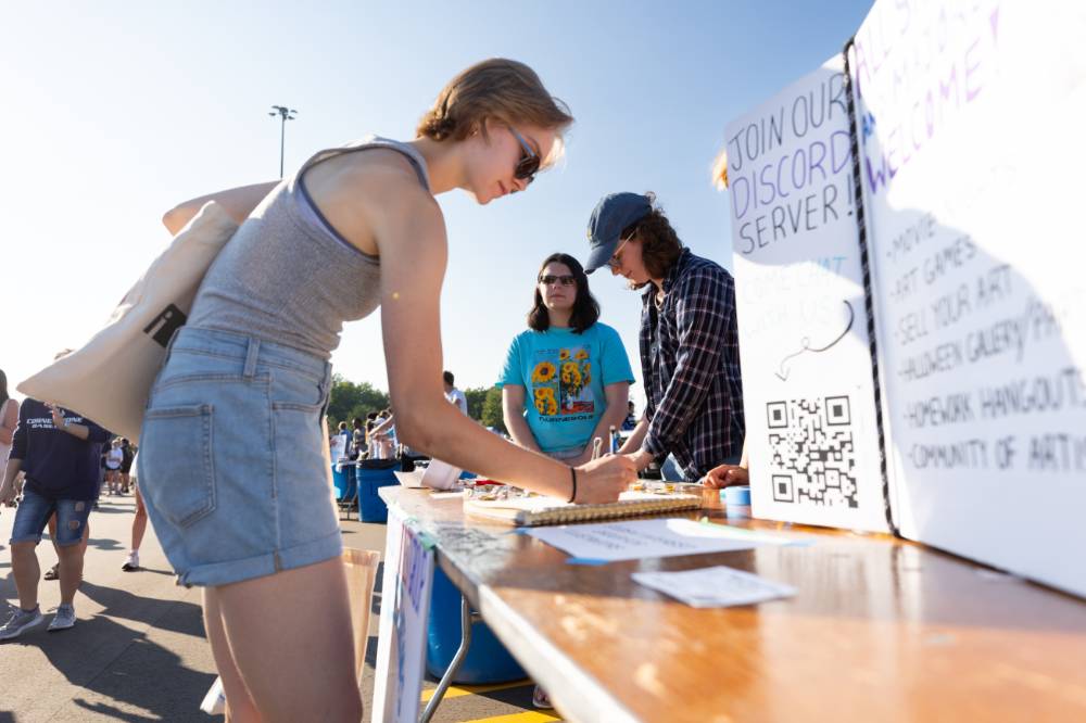 a student signing up at a Registered Student Organization's table during Campus Life Night